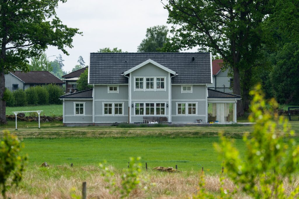 A picturesque gray house in a serene countryside setting surrounded by greenery.